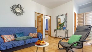 A living room with a blue sofa, a black chair, a small table with a tray of snacks, and a decorative mirror. - Charming Farmhouse Retreat in Santa Ursula, Tenerife (santa ursula)