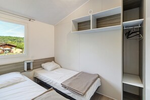 Une chambre avec deux lits, une fenêtre et une armoire avec une tringle pour suspendre les vêtements.