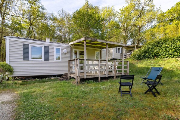 Une maison mobile dotée d’une véranda, de deux chaises et d’une petite terrasse.