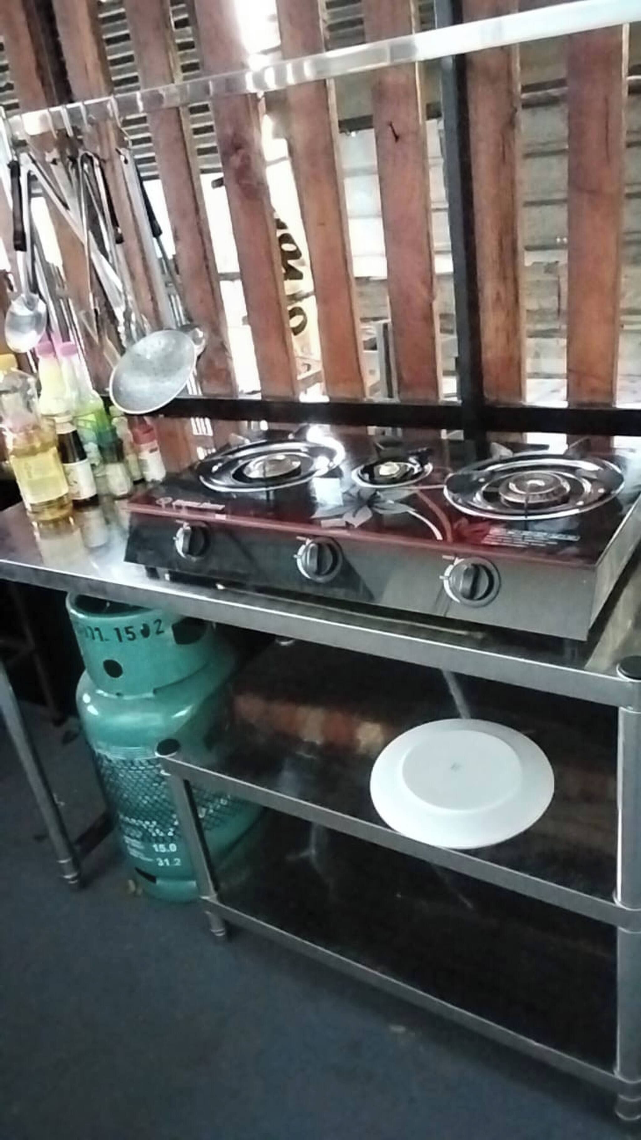 Eine Küchenzeile mit Gaskochfeld, Edelstahl-Schränken und Gasflasche.