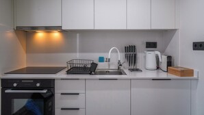 Een moderne keuken met witte kasten, een roestvrijstalen spoelbak, een Bosch waterkoker en een vaatwasser.