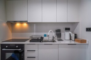 A modern kitchen with white cabinets, a stainless steel sink, a Bosch kettle, and a dishwasher. - Pothos Luxury Maisonette (Iraklio)