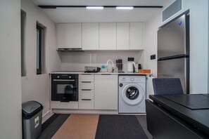 A compact kitchenette with a built-in oven, microwave, and washing machine. - Pothos Luxury Maisonette (Iraklio)