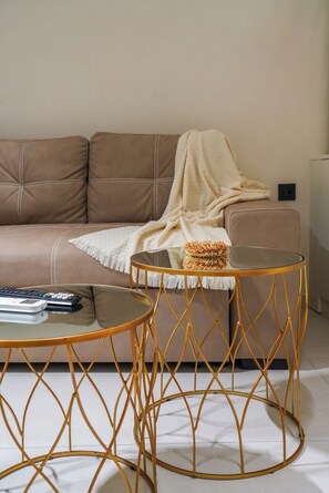 A modern living room with a sofa, two round tables, and a blanket. - Pothos Luxury Maisonette (Iraklio)
