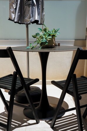 A round table with two black chairs, a potted plant, and a silver umbrella. - Pothos Luxury Maisonette (Iraklio)