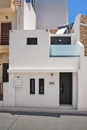 A modern building with a flat facade, a small window, a door, and a sign that reads 'Pothos.' - Pothos Luxury Maisonette (Iraklio)