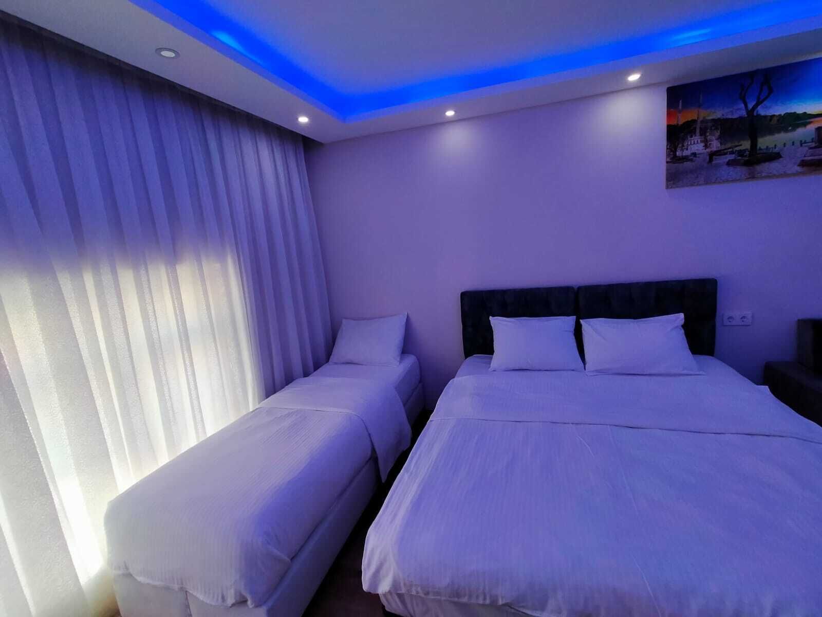 Ein Hotelzimmer mit zwei Einzelbetten, einem großen Bett und einem Gemälde an der Wand.