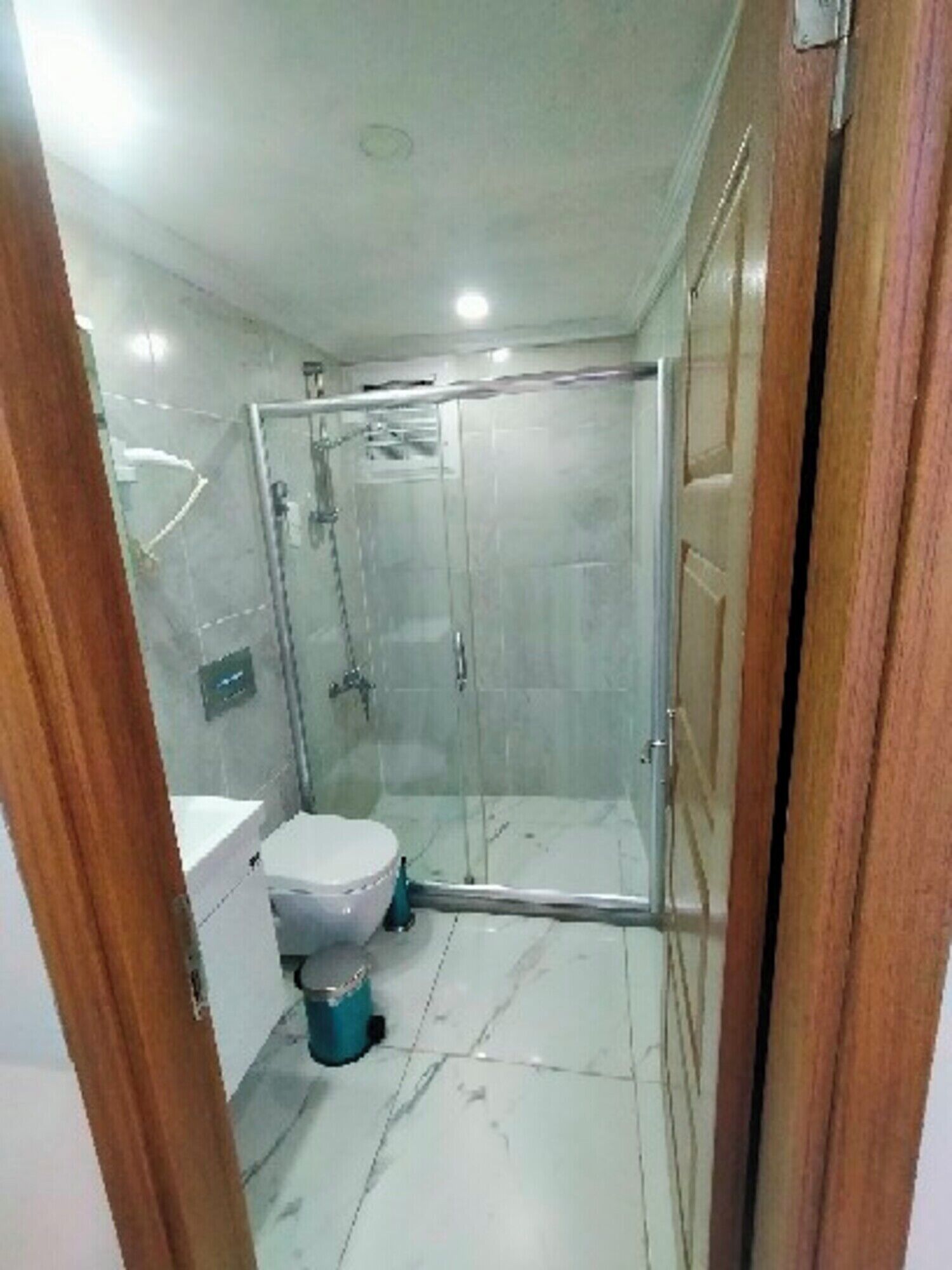 Een badkamer met een glazen douchecabine, toilet en wastafel.