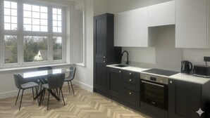 A modern kitchen with a large window, dark cabinetry, and a herringbone floor pattern.