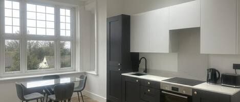 Una cocina moderna con un ventanal grande, muebles oscuros y un suelo con patrón de espiga.
