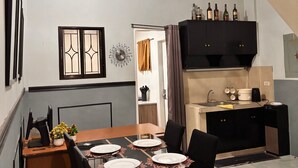 A dining area with a table set for four, a kitchen with a built-in oven, and a staircase leading to an upper level. - Axon Cozy Modern House Grey Near The Walking Street (Angeles)