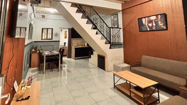 A spacious living area with a staircase, a dining table, and a sofa. - Axon Cozy Modern House Grey Near The Walking Street (Angeles)