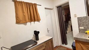 A small kitchen with a wooden cabinet, a countertop, and a window with a curtain. - Axon Cozy Modern House Grey Near The Walking Street (Angeles)