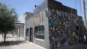 A building with a colorful mural on the side, a storefront with a sign reading "The Dressing Room," and a clear sky above.