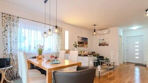 Una cucina moderna con zona pranzo, pavimento in legno e illuminazione a sospensione.