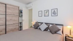 Una camera da letto con un letto, lampade sui comodini, un armadio e quadri appesi al muro.
