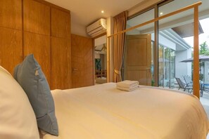A bedroom with a large bed, a wardrobe, and a sliding glass door leading to an outdoor area. - Trichada Resort Where the Rich Go V91 (Choeng Thale)