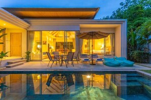Uma casa moderna com um alpendre envidraçado, piscina e mobiliário de exterior.