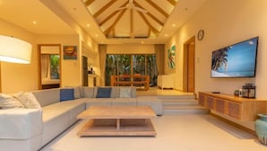 Un salón amplio con un sofá grande, una mesa de centro de madera y un televisor en la pared.