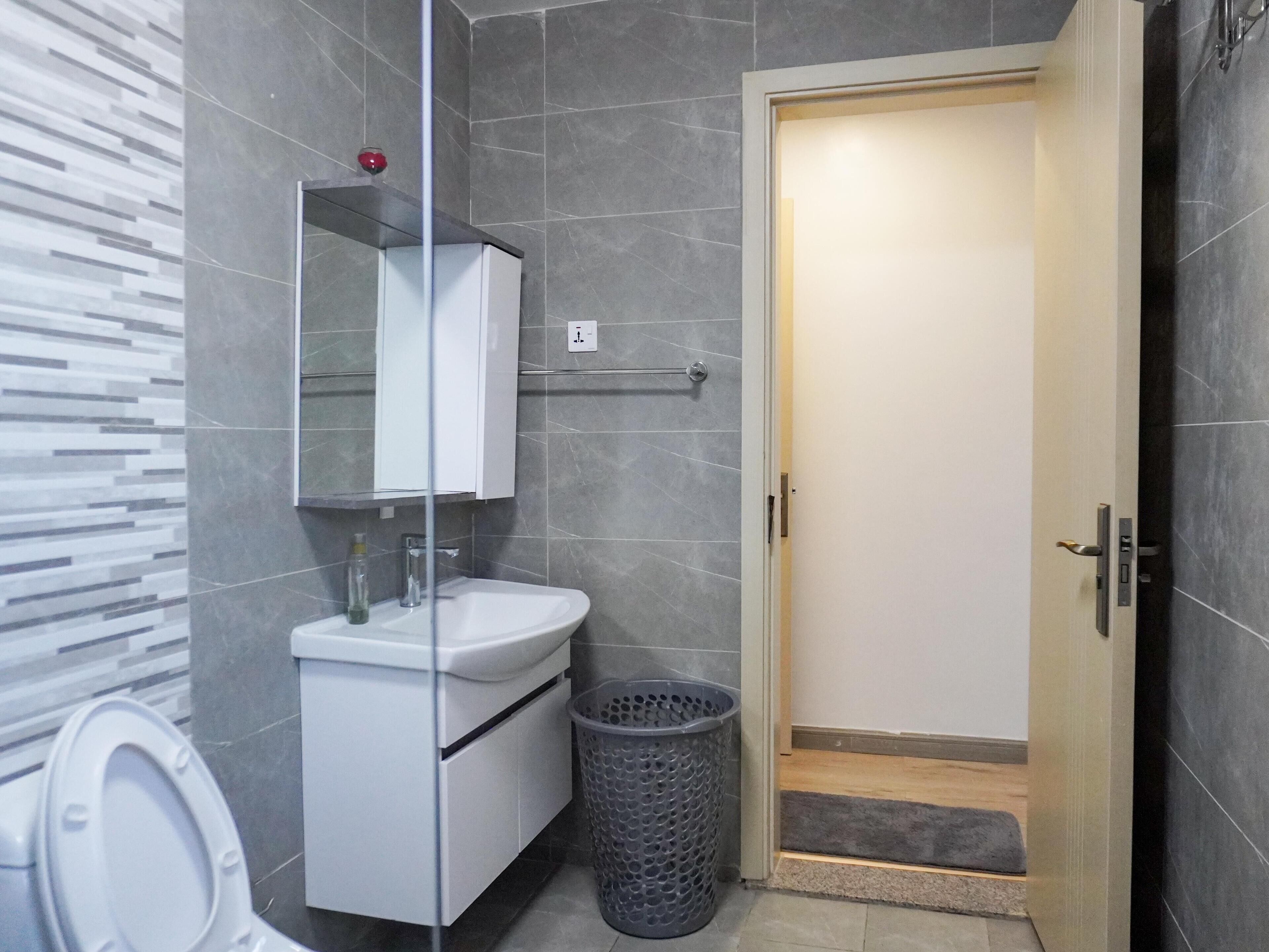 A modern bathroom with a toilet, sink, and mirror.