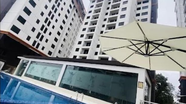 Una piscina con pared de vidrio, rodeada de edificios altos.