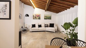 A living room with a white sofa, a coffee table, and a large plant. - Loggia Senensis (Siena)