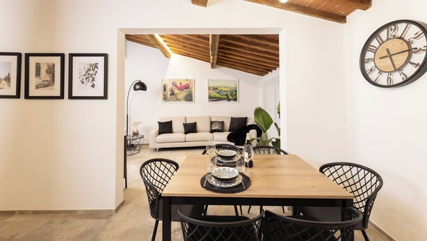 A dining area with a wooden table, black chairs, and framed artwork on the walls. - Loggia Senensis (Siena)