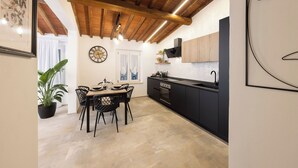 A modern kitchen with black cabinets, a wooden ceiling, and a dining area with a table and chairs. - Loggia Senensis (Siena)