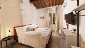 A bedroom with a bed, bedside tables, a desk, a TV, and a window with curtains. - Loggia Senensis (Siena)