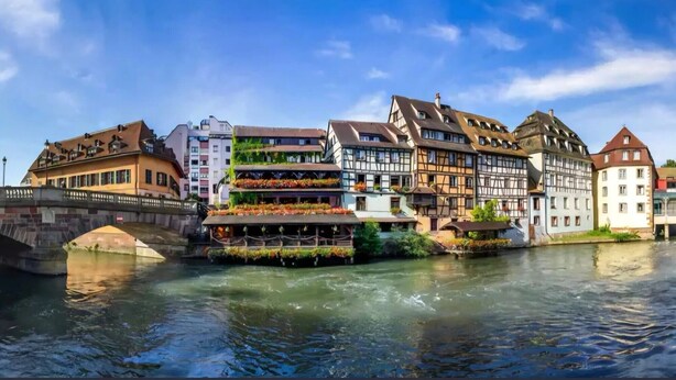 Vista del riu amb edificis europeus tradicionals, un pont i una barca.