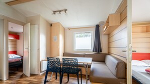 Habitació compacta amb llit, taula, dues cadires, sofà i finestra.