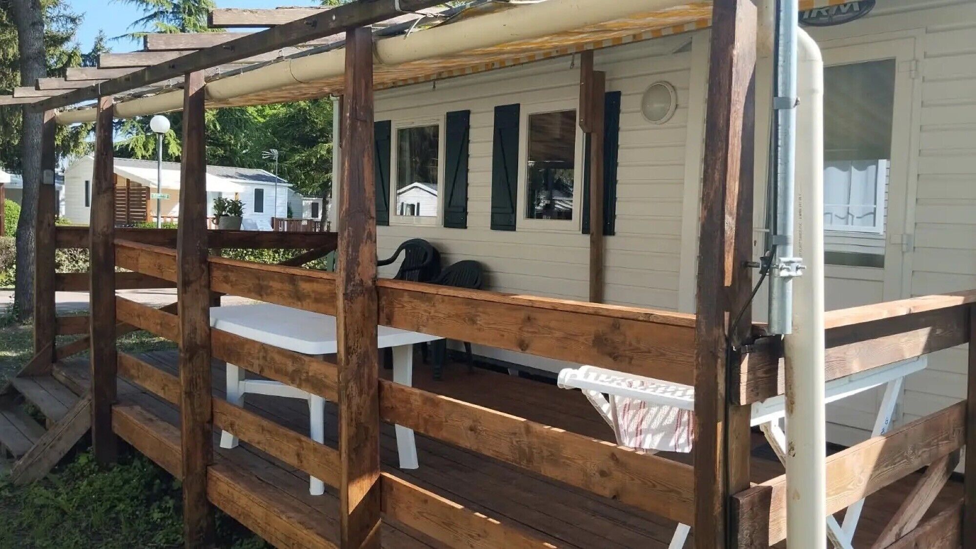 A wooden deck with white railings, a table, and chairs.