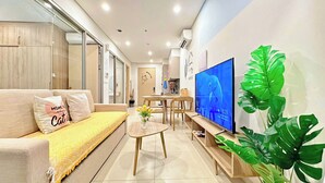 Een moderne woonkamer met een bank, salontafel, televisie en een eethoek.