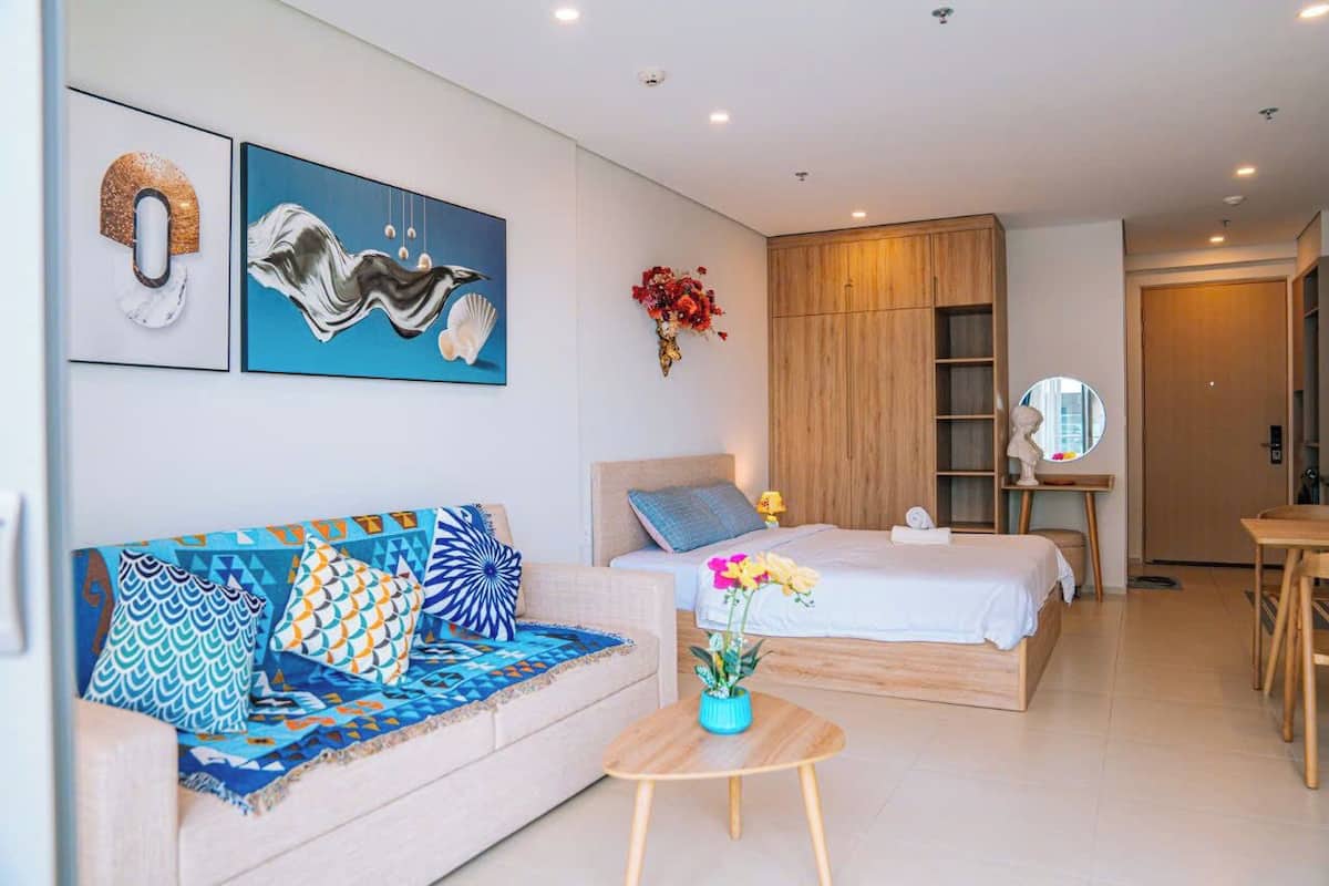 Une chambre d’hôtel moderne, équipée d’un canapé, d’un lit, d’une petite table et ornée d’œuvres d’art sur les murs.
