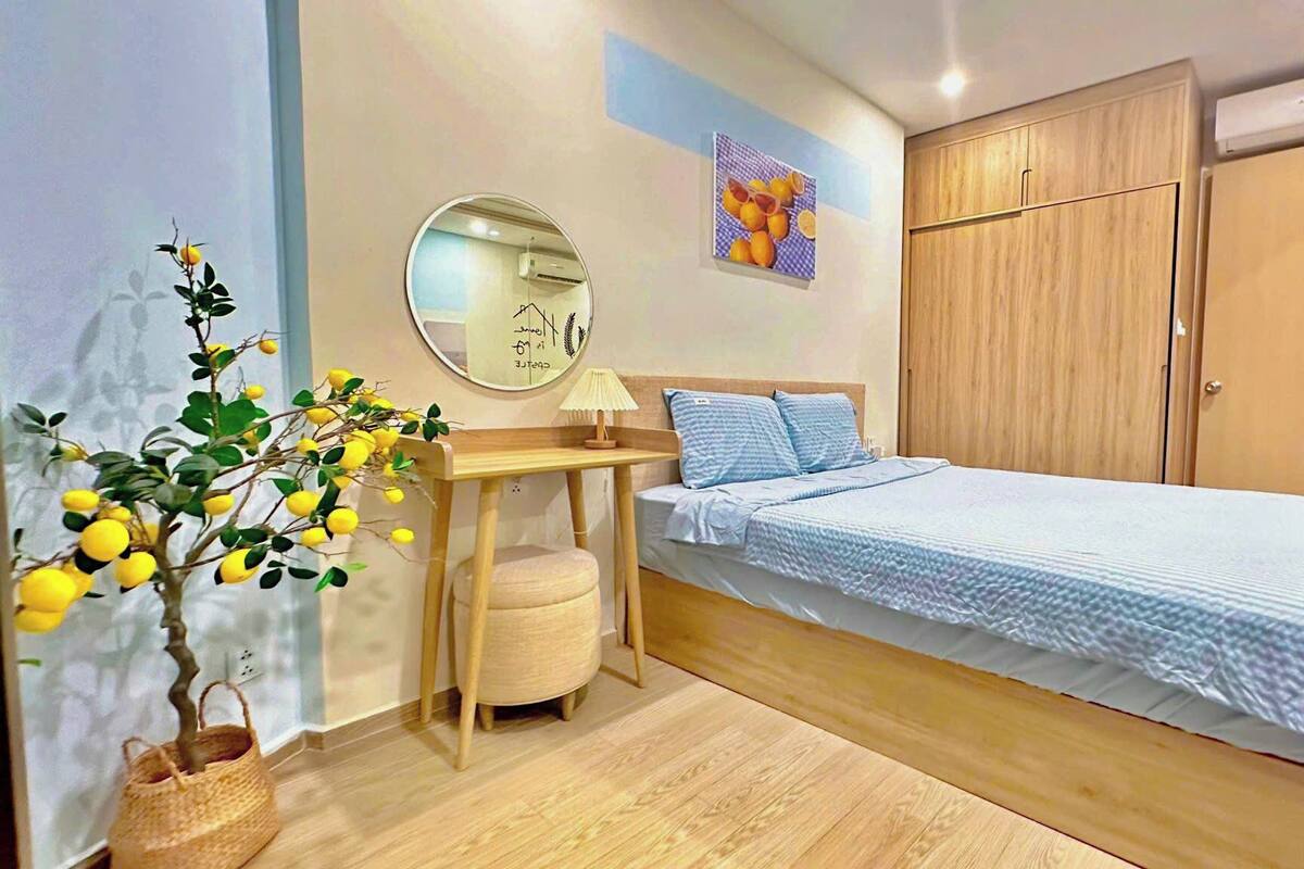 Une chambre à coucher avec un lit, une table de chevet avec une lampe, un miroir, une armoire et une plante en pot.