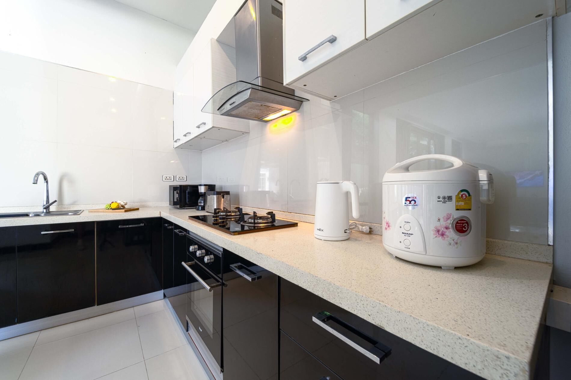 A modern kitchen with a built-in stove, a coffee maker, and a rice cooker.