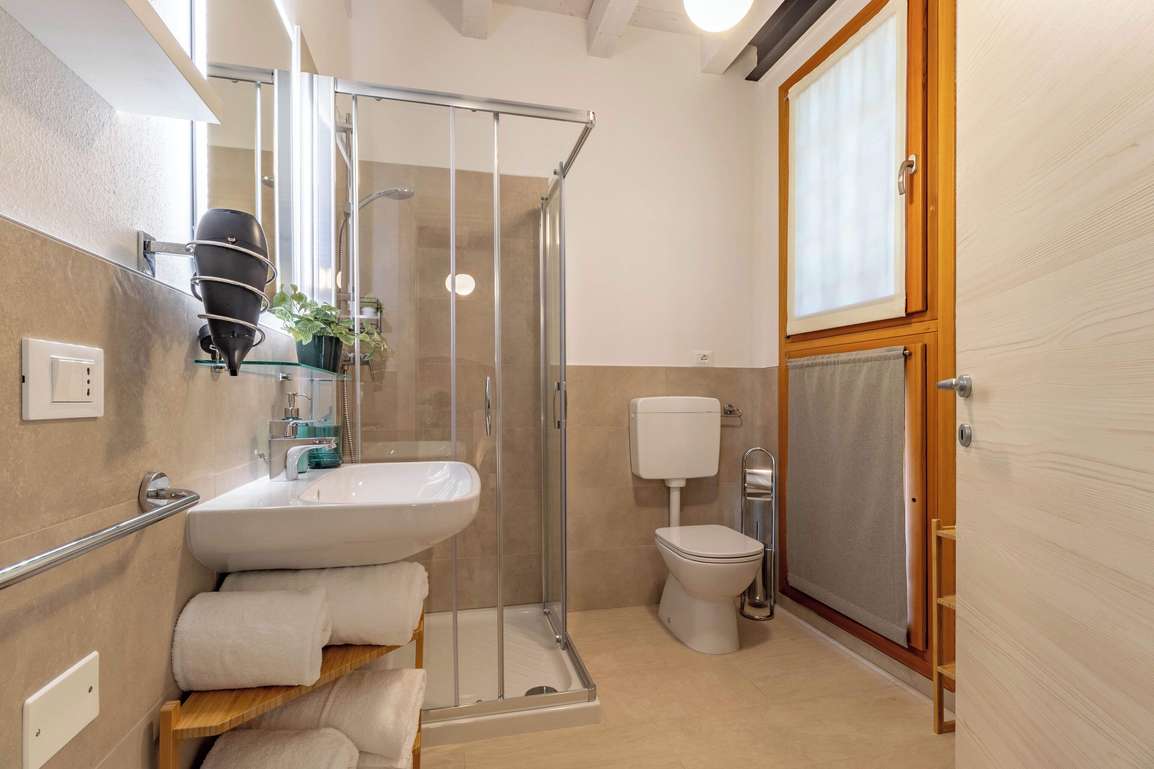 A modern bathroom with a glass shower enclosure, a white sink, and a toilet.