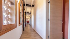 Un pasillo con suelo de madera, una puerta a la derecha y una ventana a la izquierda.