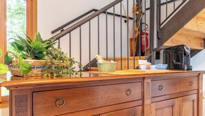Una encimera de madera con una cesta tejida, una cafetera y un extintor sobre una escalera de madera.