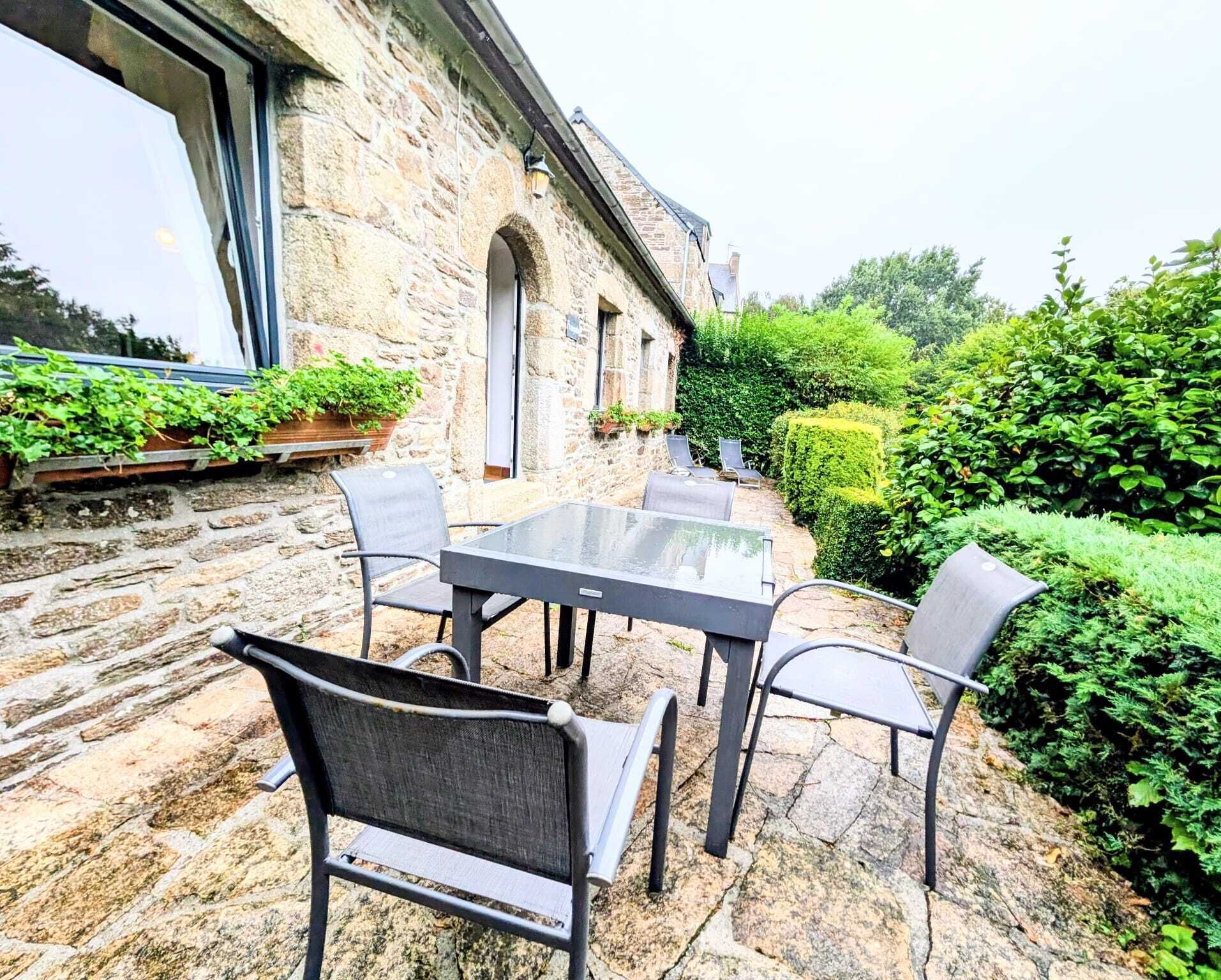 Une terrasse extérieure avec un sol en pierre, une table en verre et des chaises en métal.