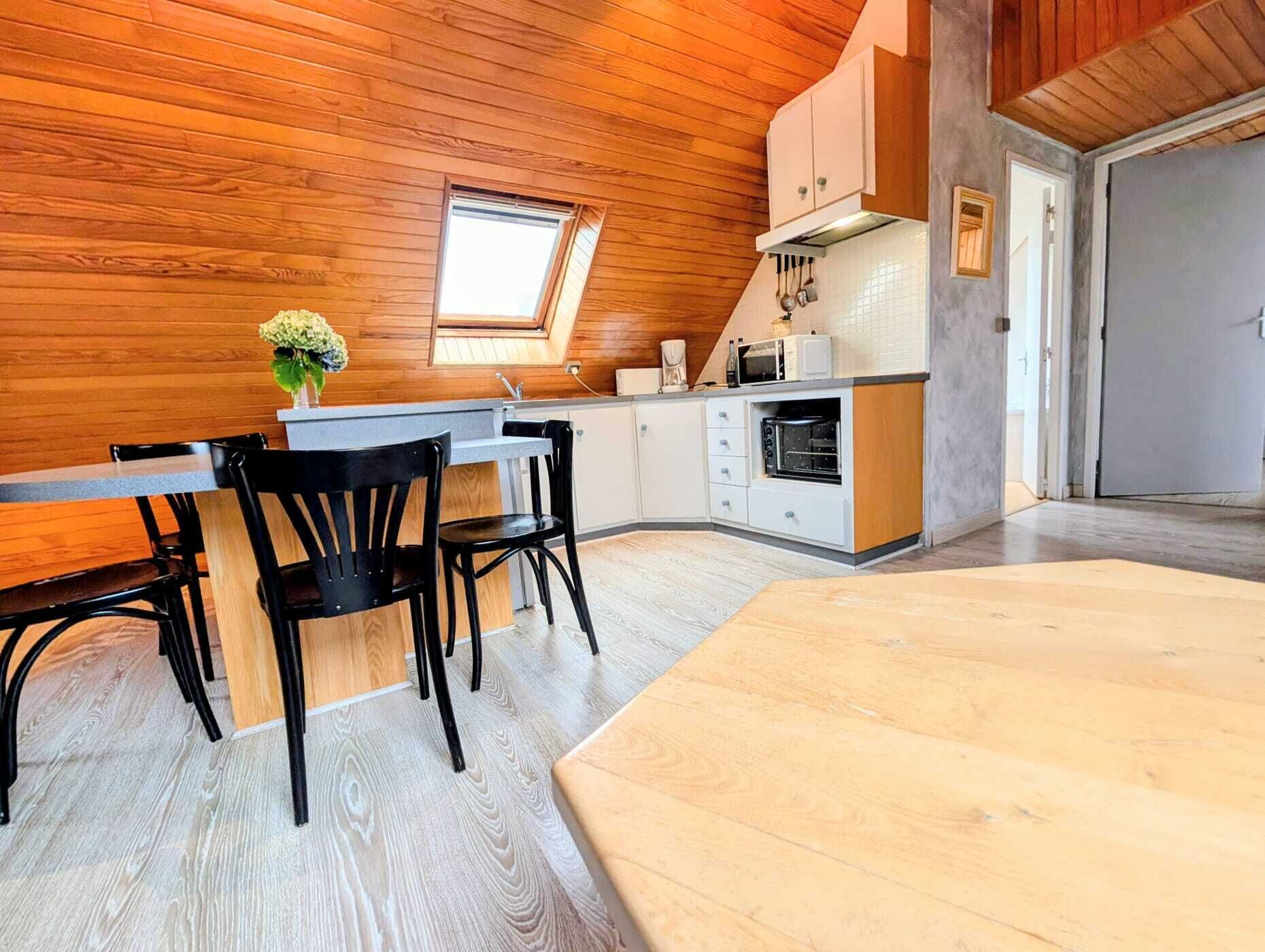 Een moderne keuken met houten wanden, een dakraam en een eethoek met een tafel en stoelen.