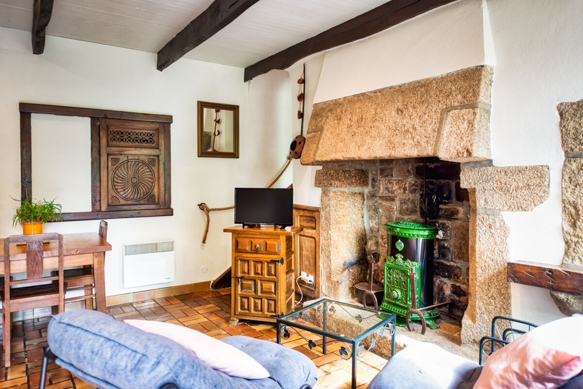 A rustic room with a stone fireplace, wooden furniture, and a television on a wooden cabinet.