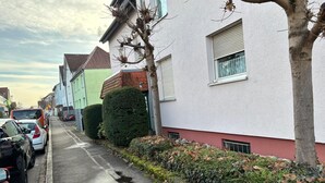 A residential street with parked cars and houses.