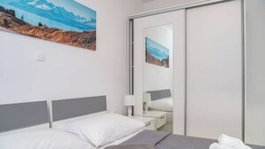 Ein Hotelzimmer mit Bett, Nachttisch, Lampe und einem großen Spiegel.
