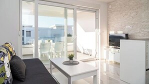 Ein modernes Apartment mit Balkon, einer Couch, einem Esstisch und einer Küchenzeile.