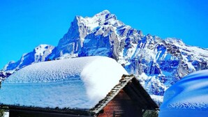 A snow-covered wooden cabin with a mountain in the background. - Concierge, Idyllic Farm, Scenic Views by SwissHut (Sigriswil)