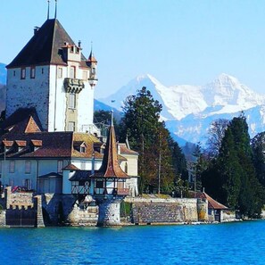 A castle with a tower, a church, and a mountain in the background. - Concierge, Idyllic Farm, Scenic Views by SwissHut (Sigriswil)