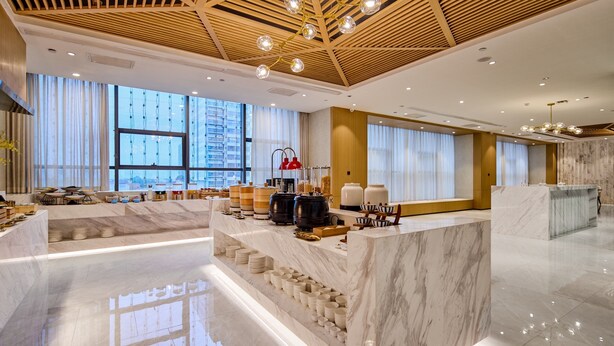 Un moderno vestíbulo de hotel con un mostrador de recepción de mármol, ventanas amplias y techo de madera.