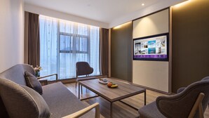 Una habitación de hotel moderna con un ventanal grande, una mesa de centro de madera y una zona de estar con dos sofás y una silla.