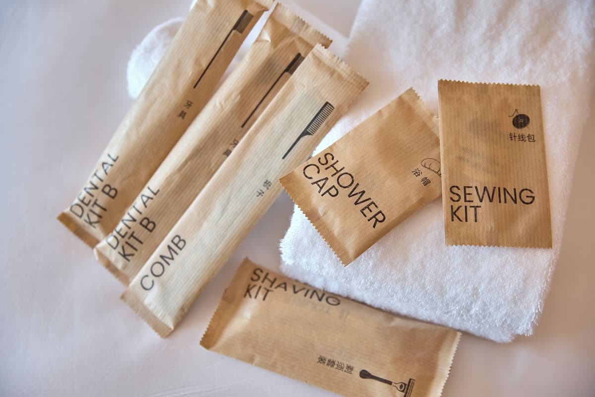 Various toiletry kits including a dental kit, comb, shaving kit, and a sewing kit, arranged on a white towel.